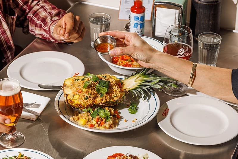 A dish made to be shared involving coriander, sweet chilli and half a pineapple