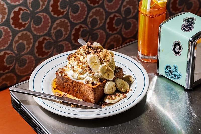 A plate bears a luxurious dessert involving chopped bananas and thick cream