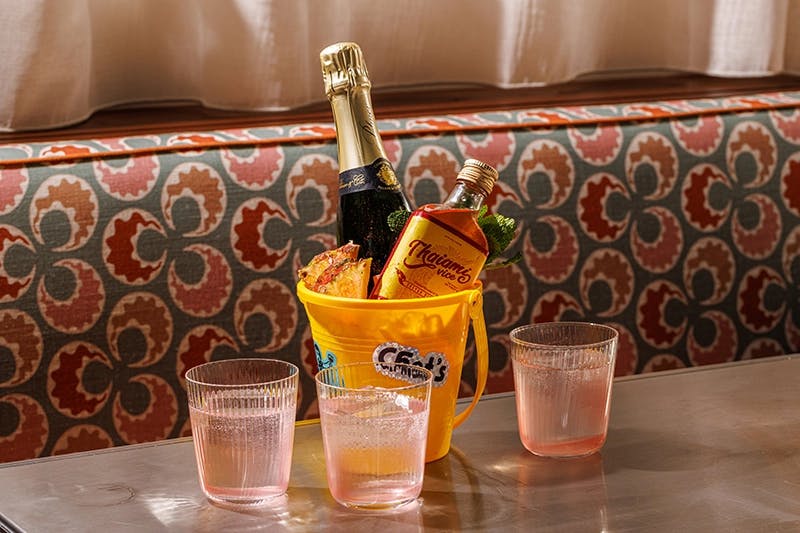 An ice bucket sits on a table with champagne and cognac bottles poking out